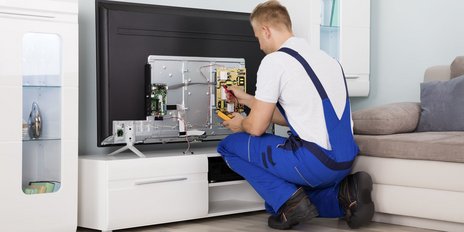 Ein Elektroniker der einen Fernseher repariert in einem Wohnzimmer