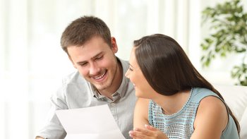 Ein Mann und eine Frau lachen sich an und halten ein Blatt in der Hand